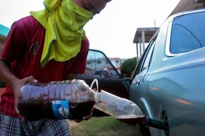 A youngster fills a car with gasoline purchased on the streets in Maracaibo, Venezuela, in August 2020