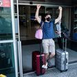A traveller, mask-clad due to the COVID-19 coronavirus pandemic, arriving on one of the first flights from Britain gestures as he walks with luggage out of the terminal at Cyprus' Larnaca International Airport on August 1