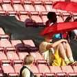 Arsenal midfielder Mesut Ozil (C) shelters from the sunshine beneath an umbrella