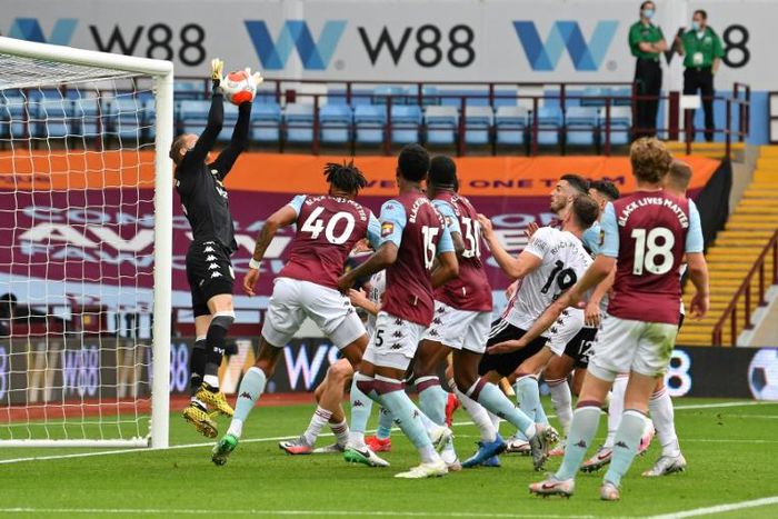 Aston Villa goalkeeper Orjan Nyland jumps to catch the ball before falling back into the goal