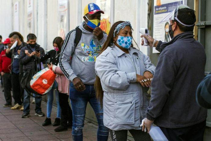 A worker checks the temperature of a customer outside a supermarket in Valparaiso on June 12 as the city went under quarantine