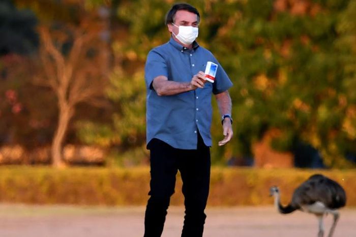 Brazilian President Jair Bolsonaro shows a box of hydroxychloroquine to supporters outside the Alvorada Palace in Brasilia
