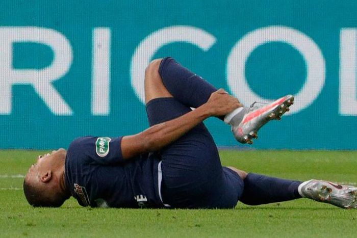 Kylian Mbappe clutches his right ankle after a foul by Loic Perrin in the French Cup final