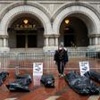 Participants in a "People's Motorcade" stop at the Trump International Hotel to deliver fake body bags during a protest against the administration's response to the COVID-19 pandemic in Washington, DC
