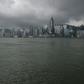 A man reads a newspaper on the edge of a promenade overlooking Victoria Harbour in Hong Kong