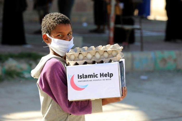 A child wearing a protective mask receives humanitarian aid in Yemen's third city of Taez, on May 8, 2020, amid the coronavirus pandemic