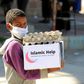 A child wearing a protective mask receives humanitarian aid in Yemen's third city of Taez, on May 8, 2020, amid the coronavirus pandemic