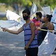 People flutter improvised white flags along a road to show their need for food during a mandatory quarantine imposed by the government against the spread of the new coronavirus in San Pedro Perulapan, El Salvador on June 10, 2020