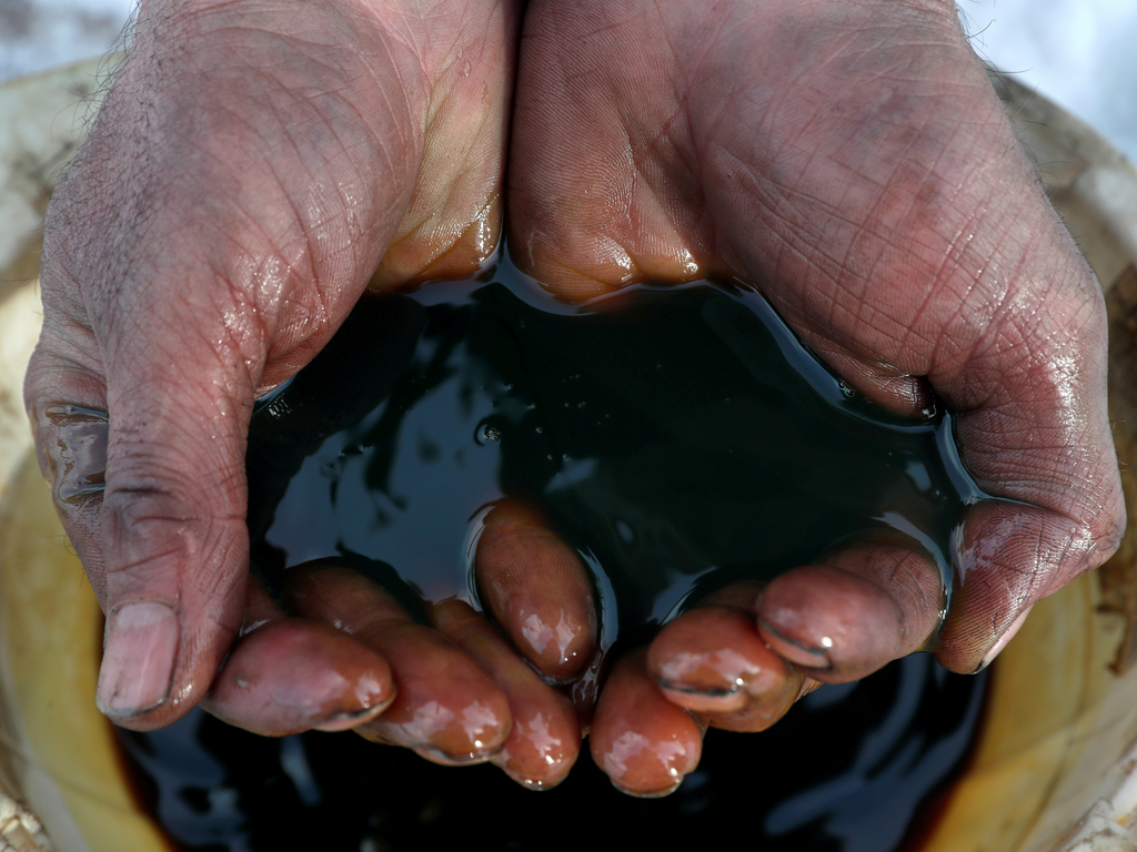 FILE PHOTO: An employee demonstrates a sample of crude oil in the Yarakta Oil Field, owned by Irkutsk Oil Company (INK), in Irkutsk Region, Russia in this picture illustration taken March 11, 2019. REUTERS/Vasily Fedosenko/Illustration/File Photo