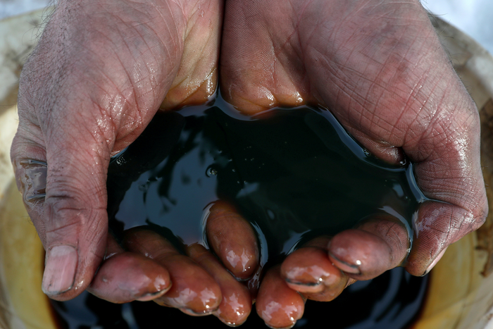 FILE PHOTO: An employee demonstrates a sample of crude oil in the Yarakta Oil Field, owned by Irkutsk Oil Company (INK), in Irkutsk Region, Russia in this picture illustration taken March 11, 2019. REUTERS/Vasily Fedosenko/Illustration/File Photo