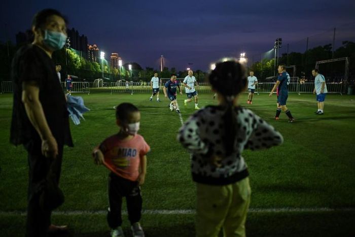 People play football in a field in Wuhan, in China's central Hubei province after coronavirus restrictions were eased