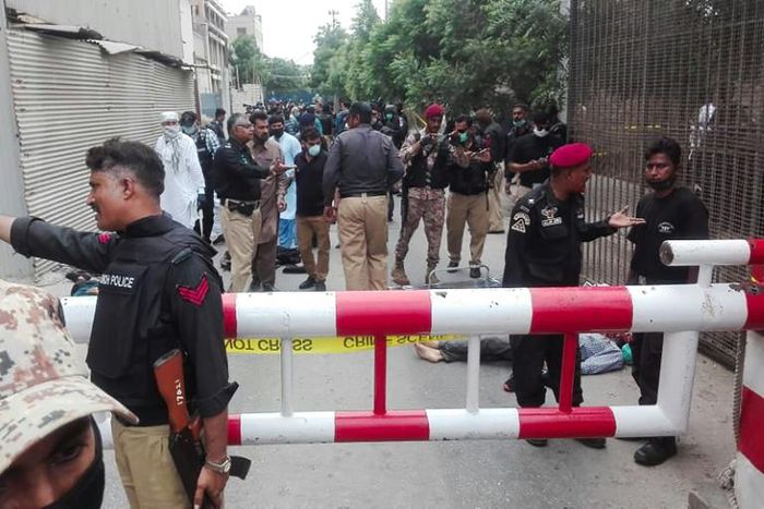 Policemen secure an area around a body outside the Pakistan Stock Exchange building after a group of gunmen attacked the building in Karachi