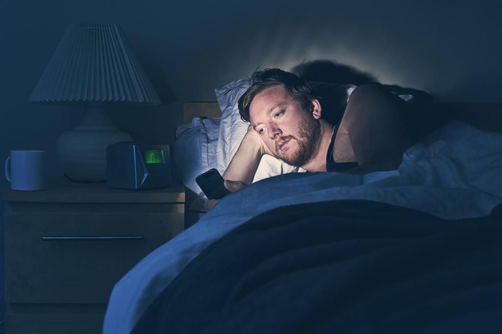 Male using Smartphone in Bed at Night