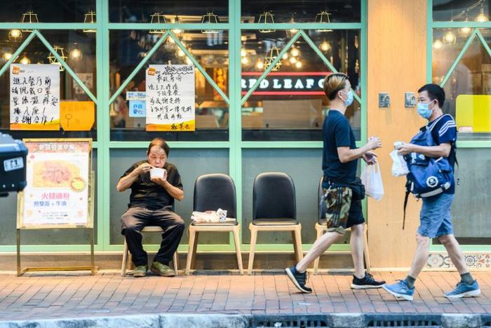 A man eats a takeaway meal outside a restaurant in Sham Shui Po, Hong Kong, after the dine-in ban was introduced