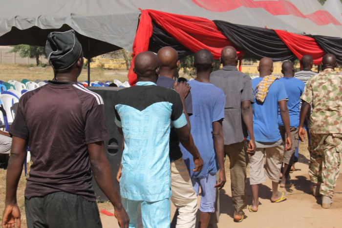 Men and boys released from Giwa Barracks after months or years of unlawful detention walk in a line as they are handed over to state officials in charge of a 'transit centre' where they will be held before returning to their communities, 27 November 20...
