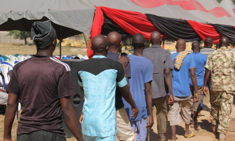 Men and boys released from Giwa Barracks after months or years of unlawful detention walk in a line as they are handed over to state officials in charge of a 'transit centre' where they will be held before returning to their communities, 27 November 20...