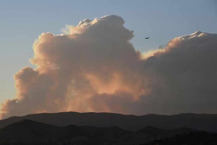 A plane flies past smoke from the Lake Fire in the Angeles National Forest