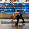 A worker cleans glass in the seafood section of a supermarket in Beijing, where a fresh coronavirus outbreak is keeping customers away