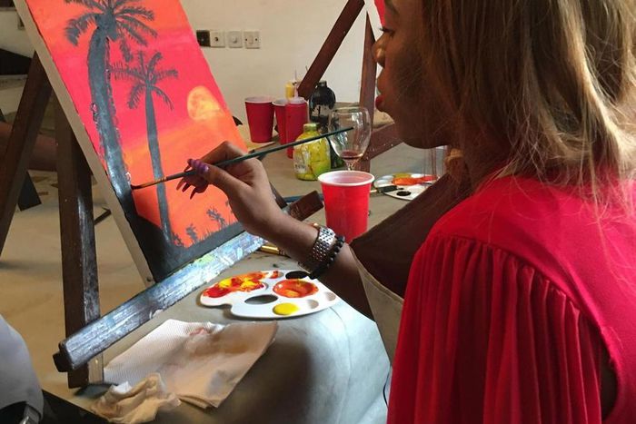 A lady painting at a sip and paint event [Instagram/sipandpaintng]