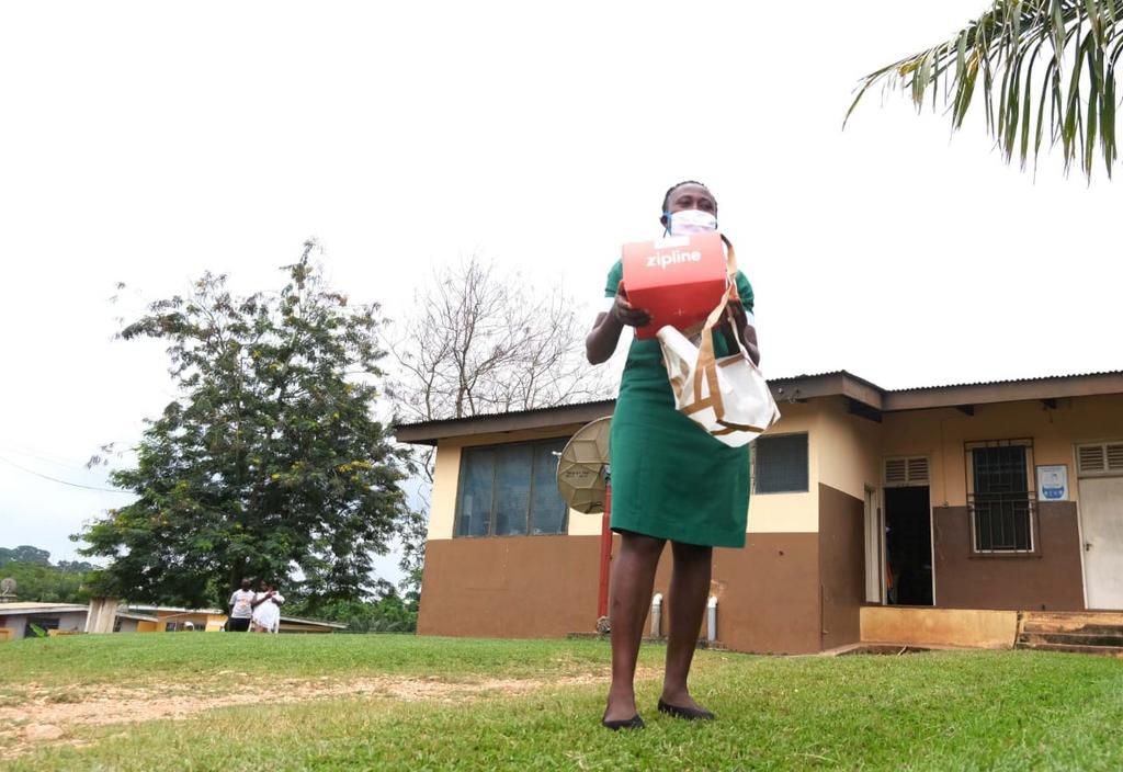 A healthcare worker at the Apedwa health center in Ghana picks up a box of medicines dropped seconds ago by a drone
