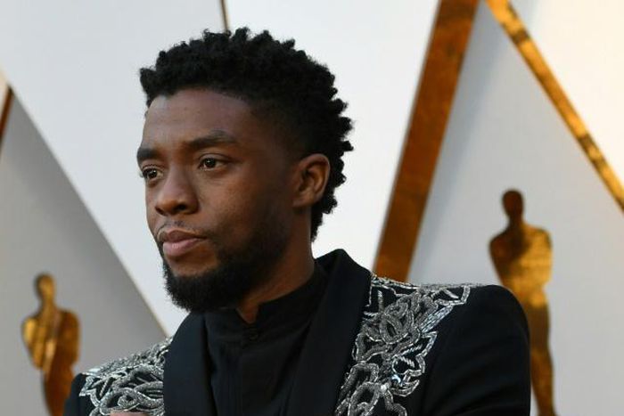 Actor Chadwick Boseman -- who plays the title role in "Black Panther" -- makes the Wakanda Forever arm gesture on the Oscars red carpet in March 2018
