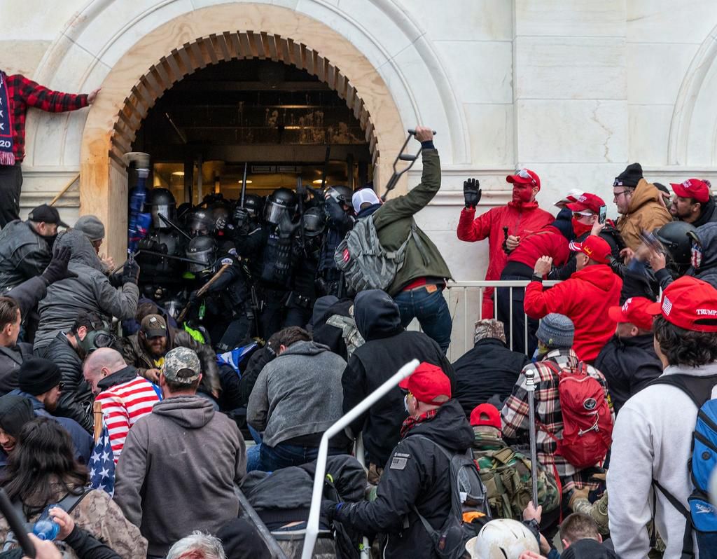Police officers in riot gear struggling to keep a pro-Trump mob from entering the Capitol.
