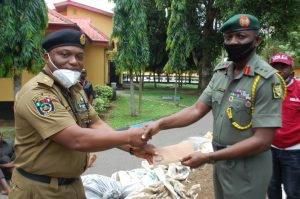 Mr Peter Bisong (L) of the NDLEA receiving the document detailing the arrest of 12 suspects in connection with peddling on illicit drugs from the Chief of Staff to the 4 Brigade Commander, Brig.-Gen. Musa Sadiq on Wednesday at the 4 Brigade headquarter...