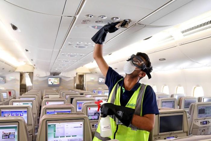 A member of the cleaning staff disinfects air vents aboard an Emirates plane; the company Medistar says its new air filtration system based on heated nickel foam can be placed inside air conditioning systems or walked through a plane via a mobile unit