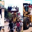 Newly wedded couple cruise in excavator as bicycle riders lead them home