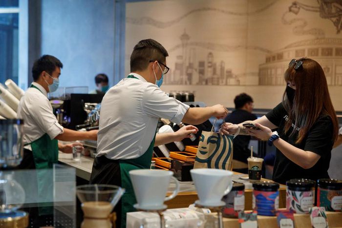 A staff member serves a customer at a Starbucks Coffee house in Beijing