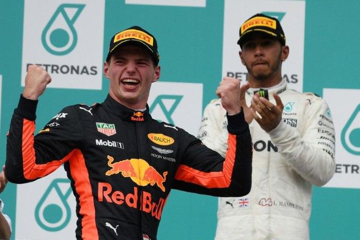 Red Bull's Dutch driver Max Verstappen (L) celebrates on the podium after winning the Formula One Malaysia Grand Prix next to second-placed Mercedes' British driver Lewis Hamilton, in Sepang, on October 1, 2017