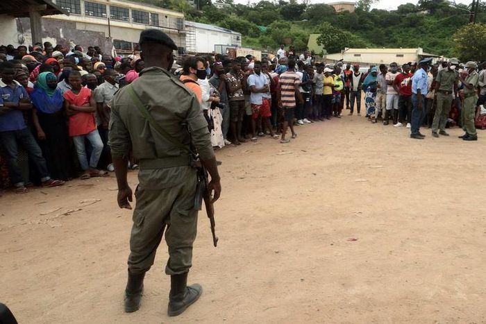 Security officials stand guard as people wait for friends and relatives fleeing an attack claimed by ISIS-linked insurgents on Palma in Mozambique, April 1, 2021.