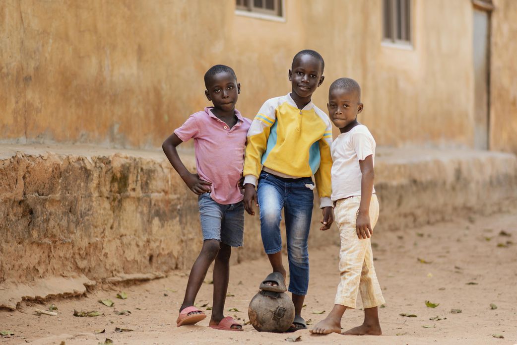 Kids posing with a ball. [Freepik]