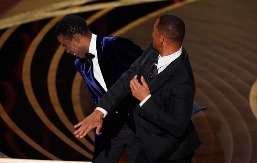 Will Smith, right, hits presenter Chris Rock on stage while presenting the award for best documentary feature at the Oscars on Sunday, March 27, 2022, at the Dolby Theatre in Los Angeles.