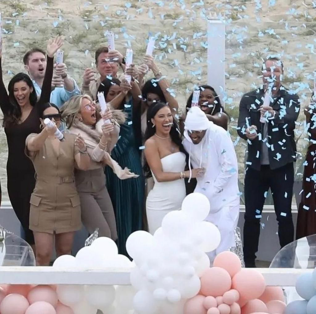 Cannon and Tiesi gathered together with a small group of friends and surrounded by pink and blue balloons.