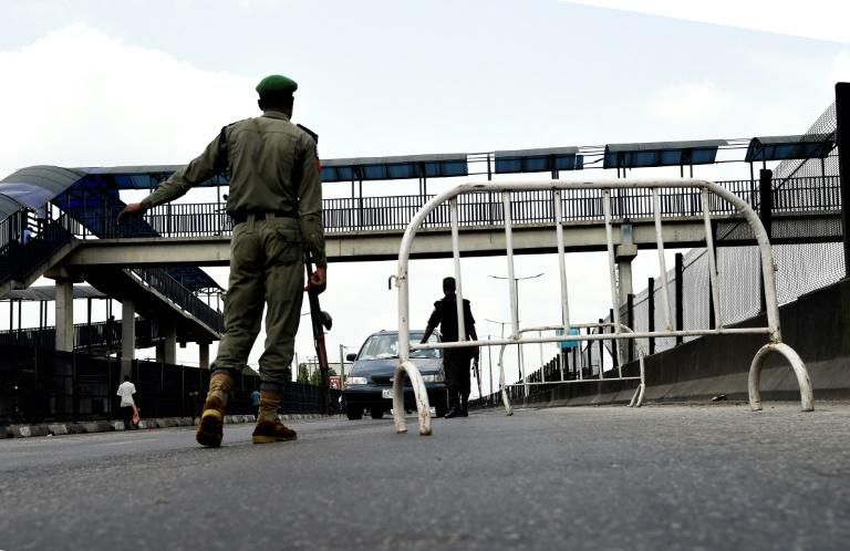 A Nigerian police officer in Lagos flags down an oncoming vehicle at a checkpoint to enforce an extended lockdown as part of measures to prevent the spread of COVID-19