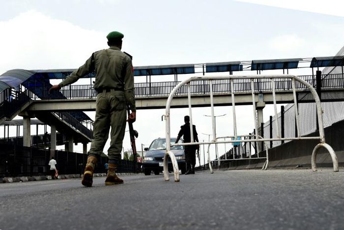 A Nigerian police officer in Lagos flags down an oncoming vehicle at a checkpoint to enforce an extended lockdown as part of measures to prevent the spread of COVID-19