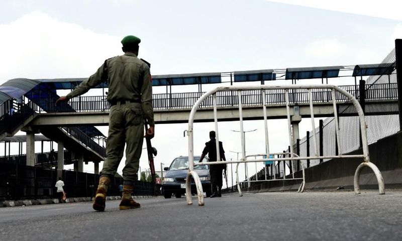 A Nigerian police officer in Lagos flags down an oncoming vehicle at a checkpoint to enforce an extended lockdown as part of measures to prevent the spread of COVID-19