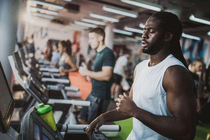 Sweaty black athlete running on treadmill in a gym.