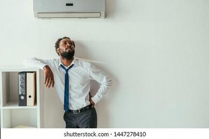A man standing under an air condition