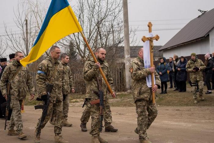 Soldiers hold the Ukrainian flag on March 16, 2020 in Starychi, Ukraine, during the funeral progression for two military servicemen killed in a Russian military strike.