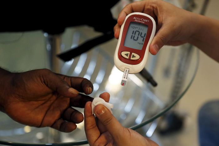 A paramedic checking the blood sugar levels of a diabetes patient.