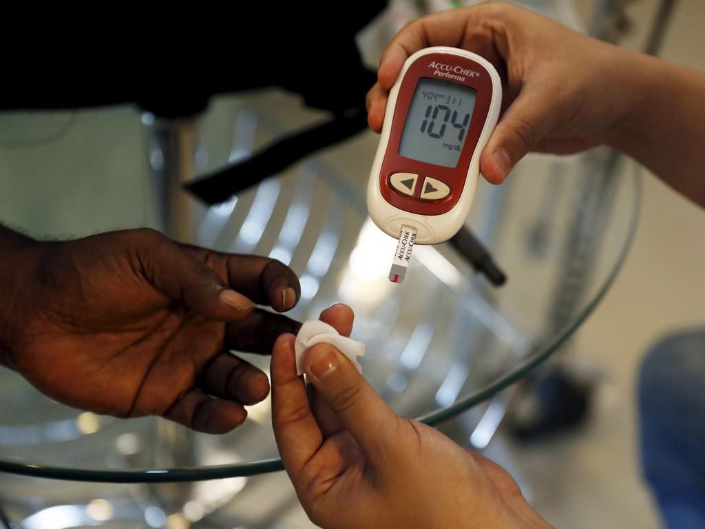 A paramedic checking the blood sugar levels of a diabetes patient.