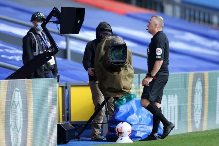 Referee Jon Moss studies a replay of an incident at Selhurst Park