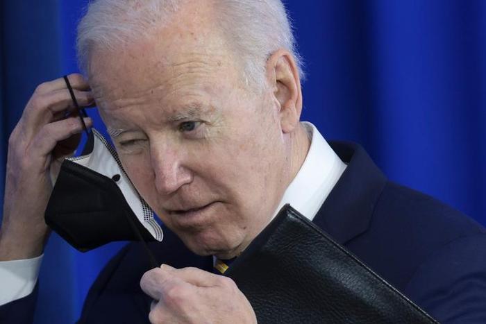 Joe Biden removes his mask before speaking at an event.