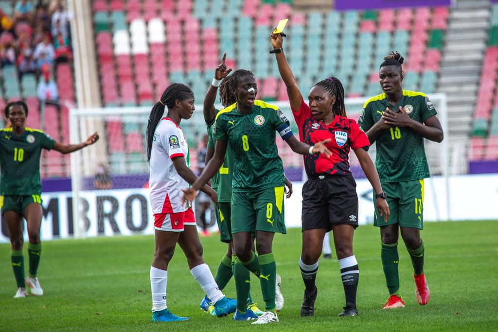 Referee Suavis Iratunga issuing a yellow card to Senegal's Mbayang Sow