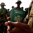 A Nigerian officer holds passports for his troops preparing to board a U.S. military plane in the Nigerian capital of Abuja