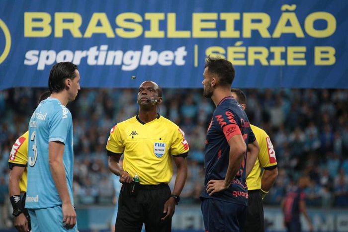 Players watch on as the referee tosses the coin