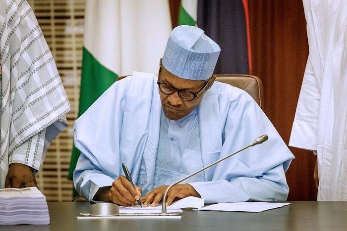 President Muhammadu Buhari signing (Premium Times)