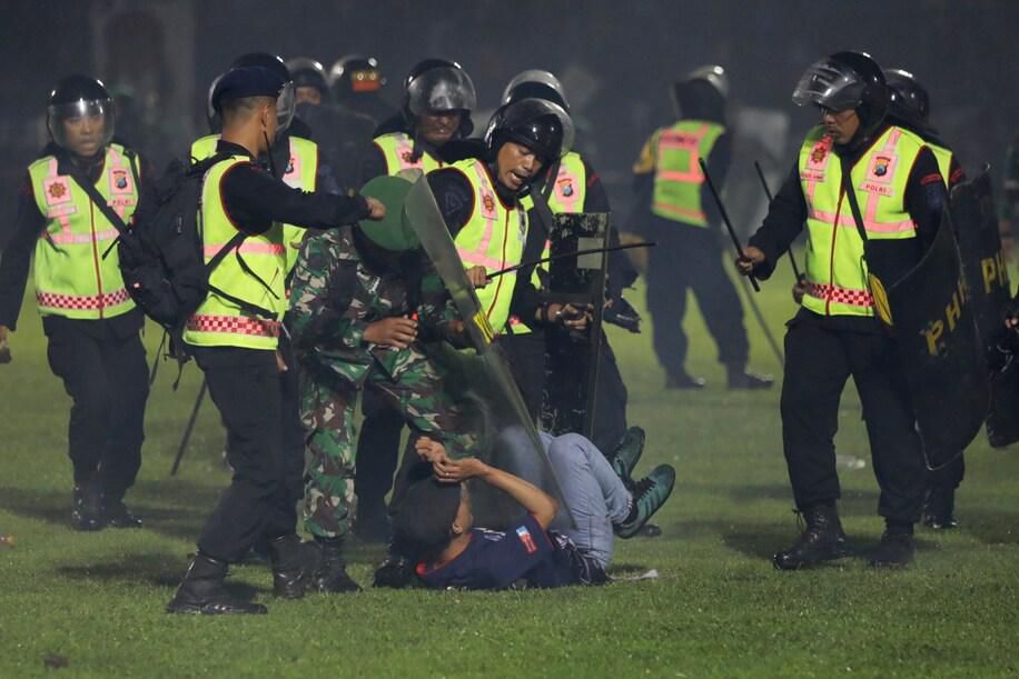 Security officers detain a fan during a clash between supporters of two Indonesian soccer teams at Kanjuruhan Stadium